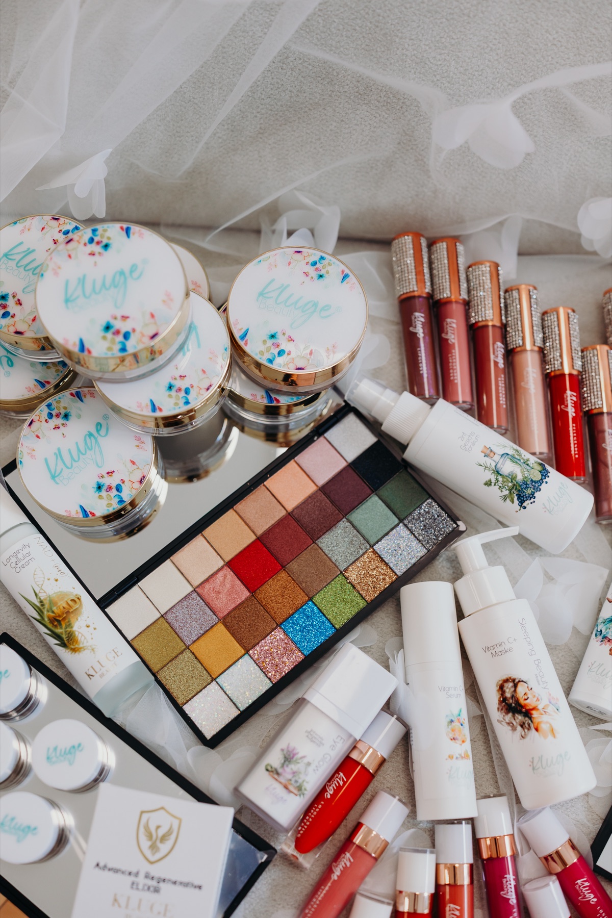 Produktwelt von KLUGE BEAUTY®: Lidschatten-Palette, Lipglosse und Puderdosen mit Konfetti