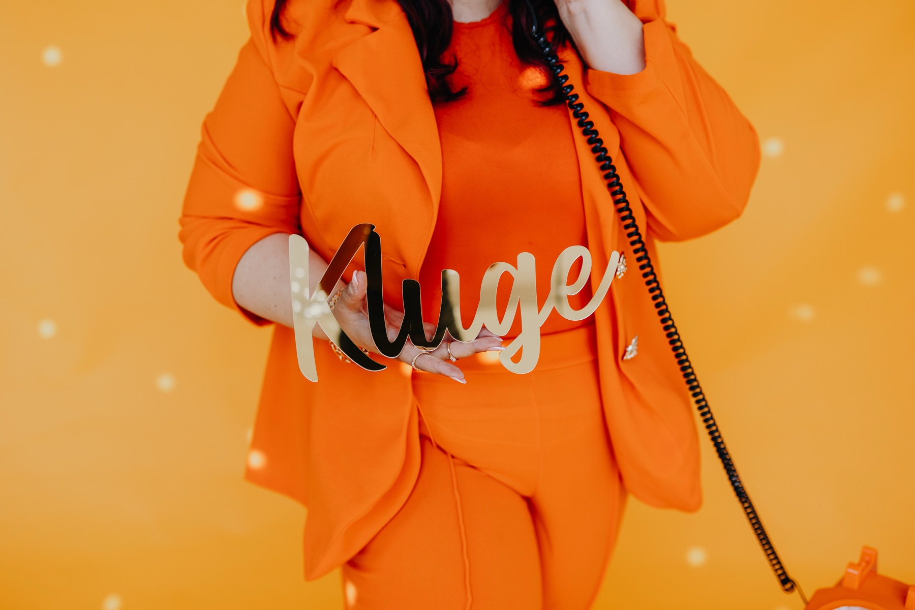 Nadine Kluge in Magenta und eine Kollegin in Orange betrachten ein Moodboard an der Wand