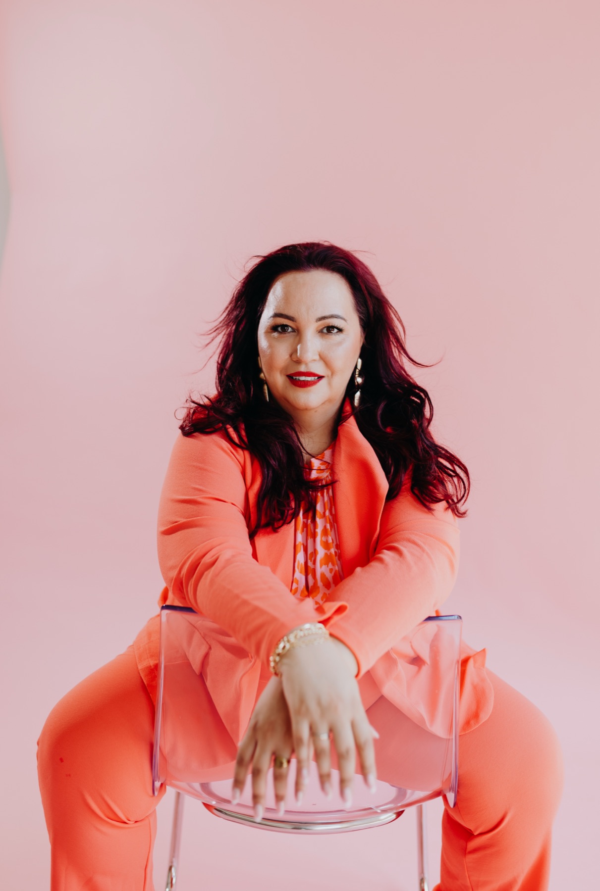 Nadine Kluge im orangen Anzug hält Produkte von KLUGE BEAUTY® in den Händen