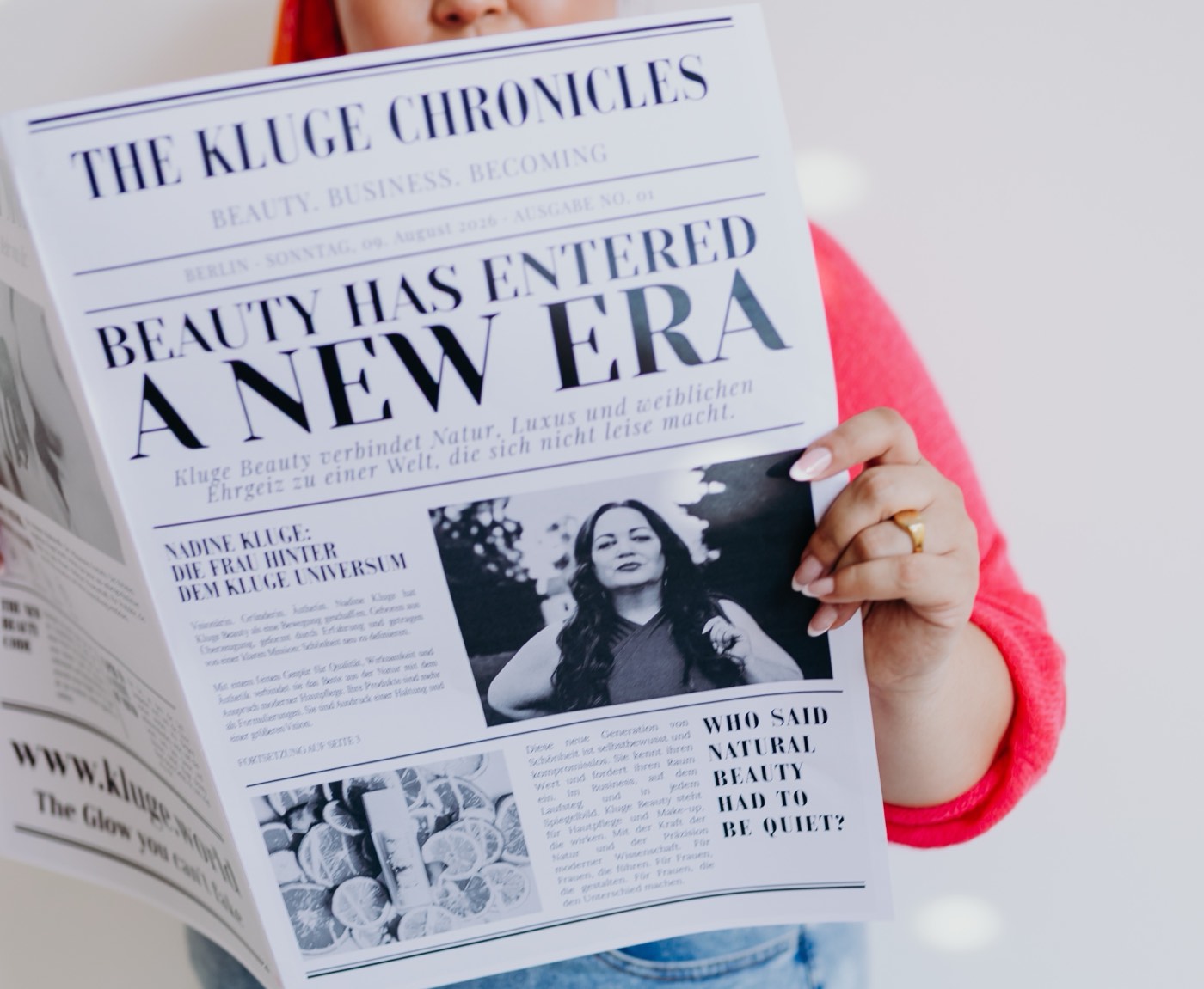Nadine Kluge hält eine gedruckte Zeitung mit dem Titel The Kluge Chronicles und der Schlagzeile Beauty has entered a new era in die Kamera